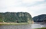 Der steil aufragende Schieferfelsen bei St. Goarshausen ist einer der bekanntesten Anziehungspunkte für Touristen im Mittelrheintal. Schon im Mittelalter war die Loreley ein bekannter Ort, zum einen wegen des markanten Felsens als Wegmarke, zum anderen wegen der für die Schifffahrt gefährlichen Stelle. An dieser Stelle lag eine Sandbank im Rhein, auf deren linker Seite das Wasser über quer im Fluss liegende Felsrippen stürzte, während es auf der anderen Seite ruhig abfließen konnte. Die verschieden schnell fließenden Wassermassen trafen sich hinter der Sandbank, wodurch dort starke Strudel entstanden, die manchem Schiffer zum Verhängnis wurden. Daraus entstand auch das Märchen der Loreley, die wahlweise durch ihren Gesang oder ihre Schönheit die Rheinschiffer in ihren Bann zieht, woraufhin diese durch die gefährliche Strömung und die Felsenriffe umkommen. Völlig unbeeindruckt von solchen Schauermärchen kommt ein Güterzug mit einer 50er aus dem Loreley-Tunnel gefahren.  (11.06.1955) <i>Foto: Carl Bellingrodt</i>