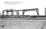 Bau der Rendsburger Hochbrücke über den Nord-Ostsee-Kanal. Für die Brücke wurden 17740 t Stahl mit 3,2 Millionen Nieten zusammengefügt. Der Bau kostete 13,4 Millionen Mark. Unten fährt ein Personenzug mit einer pr. P 4.2 (Baureihe 36) an der Baustelle vorbei mit der bereits errichteten Durchfahrtsöffnung für die künftige Schleifenauffahrt. (1912) <i>Foto: RVM-Archiv</i>