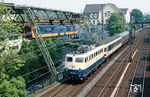 110 479 (Bw Dortmund-1) trifft mit E 3118 nach Mönchengladbach auf den Schwebebahnzug Nr. 13 in Wuppertal-Barmen. Nach gefühlt dutzenden Versuchen an dieser Stelle, Eisenbahn und Schwebebahn auf ein Bild zu bekommen, hat es diesmal endlich geklappt. Hinter der Lok hängt der "Karlsruher Steuerwagen" aus einem S-Bahn Prototypzug, zu dem auch die passend in ozeanblau/beige lackierte 141 248 gehörte. Letztlich konnte der Zug im S-Bahn-Dienst nicht überzeugen, auch wegen der vergleichsweise mäßigen Beschleunigung der Lokomotive. Die Wagen liefen daraufhin im normalen Nahverkehr mit, was jedoch nicht ohne Einschränkungen möglich war, da die Einstiege nur an Hochbahnsteigen nutzbar waren. (20.05.1989) <i>Foto: Joachim Bügel</i>