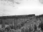 Nachdem am 12. Juni 1965 die 240 m lange und 42 m hohe Brücke mit Stahl-Vollwandträgern erfolgreich eingeschoben worden war, rollt der Verkehr über die neue Brücke. Eine Neukessel-01 überquert mit E 577 nach Nürnberg die auf drei Pfeilern ruhende neue Konstruktion (die alte Brücke liegt dahinter) auf der Bahnstrecke Waiblingen – Schwäbisch Hall-Hessental zwischen Kleinhegnach und Neustadt den Unterlauf der Rems. (19.06.1965) <i>Foto: Jörg Schulze</i>