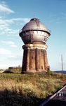 Der Bebraer Wasserturm der Bauart Klönne wurde 1910 zur Versorgung der Lokomotiven fertiggestellt. Das Bauwerk ist ein kegelförmiger Turmunterbau aus Mauerwerk mit integrierten Mauerwerksstützen zur Lastaufnahme, darüber ein aufgesetzter Stahlbehälter mit einem gurtungsähnlichen, umlaufenden Wandelgang für Wartungsarbeiten am Behälter. Auf dem Turm befindet sich der Wasserbehälter mit ca. 500 Kubikmetern Größe. Das Wassser wurde der Fulda entnommen. Nach dem Ende des Dampfbetriebs drohte 1984 der Abriss des Wasserturms. Die Stadt Bebra übernahm 1985 den Turm von der Bahn und sanierte ihn. Heute ist er ein geschütztes Industriedenkmal und Wahrzeichen der Stadt Bebra.  (1974) <i>Foto: Dr. Steinke</i>