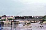 012 081 rumpelt mit dem D 820 nach Westerland/Sylt über die Klappbrücke am Husumer Außenhafen, die 1979 gegen eine Waagebalkenbrücke ersetzt werden sollte. Links am Bildrand ist noch das Stellwerk „Br“(ücke) zu erkennen. (13.08.1972) <i>Foto: Helmut Dahlhaus</i>