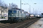 150 059 wartet im Bahnhof Solingen-Ohligs die Überholung des D 2740 (Braunschweig - Köln) ab, dessen Silhouette mit 114 494 über den leeren Flachwagen des Güterzuges auftaucht. (18.04.1988) <i>Foto: Joachim Bügel</i>