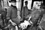 Schritt 3: Die brennende Putzwolle wird von Lokführer August Schmale in die Feuerbüchse der 043 121 geworfen. Auf der anderen Seite wartet der Heizer mit der Hand am Ölregulierschieber, um die Brenner zu zünden.  (1974) <i>Foto: Wolfgang Staiger</i>