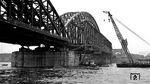 Nachdem am 6. März 1945 die Brückenpfeiler der Kölner Hohenzollernbrücke durch die deutsche Wehrmacht gesprengt worden waren, begann 1946 der Wiederaufbau. In einem ersten Schritt wurden die beiden südlichen uferseitigen Bögen in Deutz und am Kölner Hauptbahnhof angehoben und durch eine provisorische Rechteckkonstruktion (sog. Schaper-Krupp-Reichsbahn-Brücke) verbunden. So konnte am 8. Mai 1948 der Bahnverkehr über den Rhein zunächst auf zwei Gleisen wieder aufgenommen werden. Der provisorische Mittelteil wurde 1952 von Schwimmkränen aus der Brückenkonstruktion herausgezogen und durch einen Bogen ersetzt. Das Bild zeigt den ausgebauten Notbehelf neben dem neu eingebauten Mittelteil. (11.1952) <i>Foto: Karl Wyrsch, Slg. D. Ammann</i>